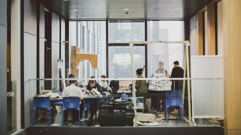 A mixed group of students are sat at tables studying and learning.